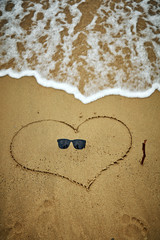 Heart shaped symbol on a sandy beach in summertime.