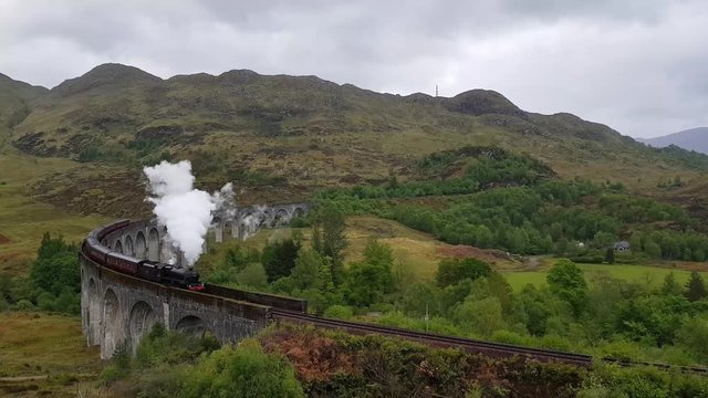 Glenfinnan Railway Viaduct in Scotland with the Jacobite steam train in summer with rainy weather. The Jacobite steam train, also known as Hogwarts Express in Harry Potter movies.