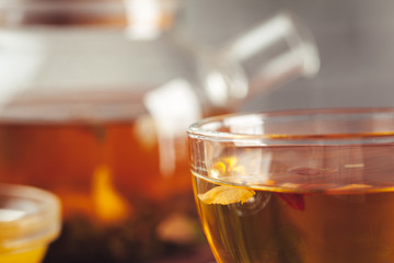 glass teapot with cup of black tea on wooden table