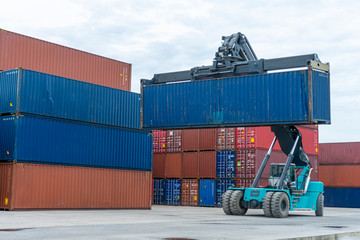 Forklift truck lifting cargo container in shipping yard