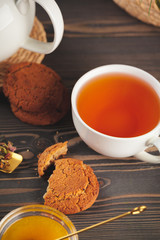 glass teapot with cup of black tea on wooden table