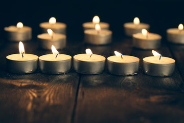 candles burning in darkness over black background. commemoration concept.