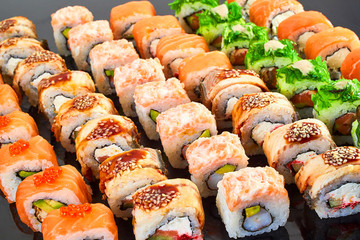 Various kinds of tasty sushi roll on black background for menu. Japanese food