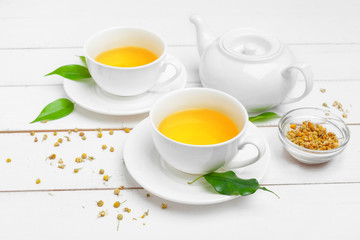 Obraz na płótnie Canvas teapot and cups of tea on a white wooden background