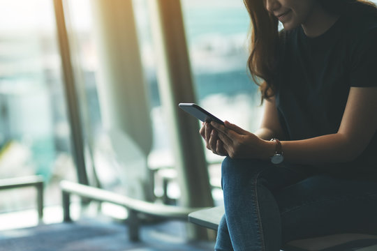 A Woman Traveler Using Mobile Phone While Sitting In The Airport