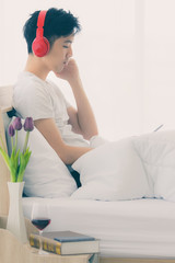 Asian man wearing red headphone, listening music.