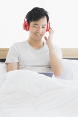 Asian man wearing red headphone, listening music..