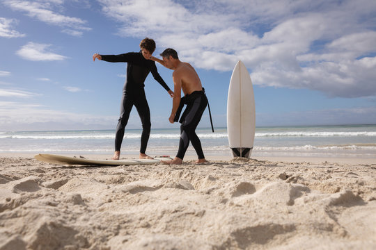 Father assist son to ride surfboard at beach - Powered by Adobe