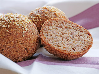Tasty almond flour bread, homemade keto buns with crust and sesame seeds over kitchen towel