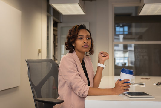 Businesswoman with coffee cup sitting on chair at office