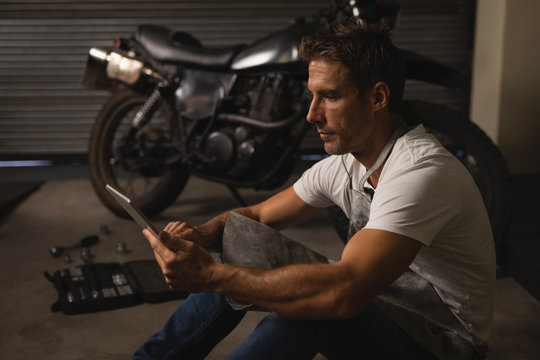 Bike mechanic using digital tablet in garage