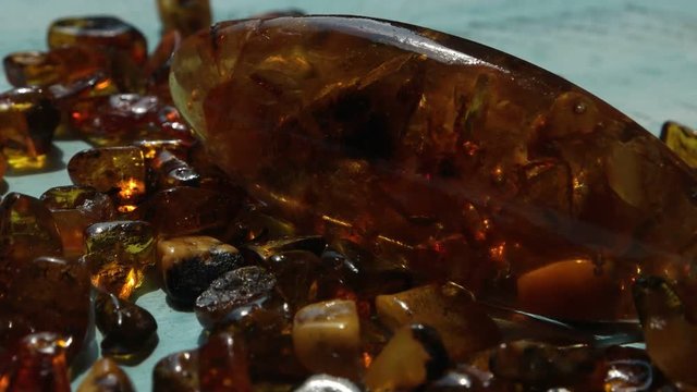 Amber cabochon and small pieces of natural baltic amber against a background of blue wooden boards