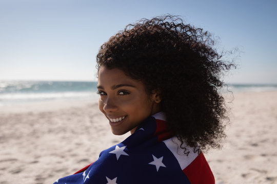 Beautiful woman holding american flag while standing at beach on a sunny day