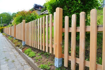 Naturfarbener Lattenzaun mit verzinktem Erdanker um einen Vorgarten als Grundstücksabgrenzung
