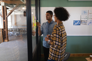 Business people writing on sticky notes in office