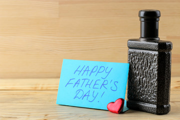 Happy father's day. text on paper and men's perfume on a natural wooden background. celebration.