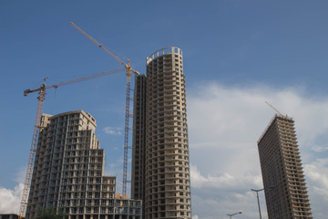 Fototapeta na wymiar Big industrial tower crane with unfinished high raised building