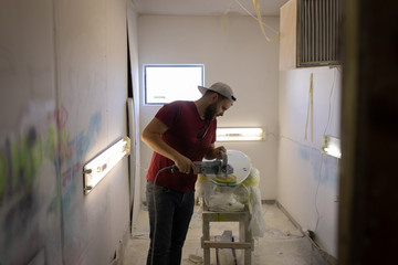 Man grinding surfboard in a workshop