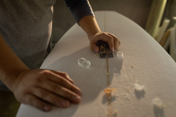 Man shaping surfboard in a workshop