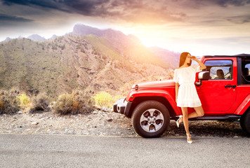 Slim young woman in summer dress and red car on road trip with landscape of moutnans  © magdal3na