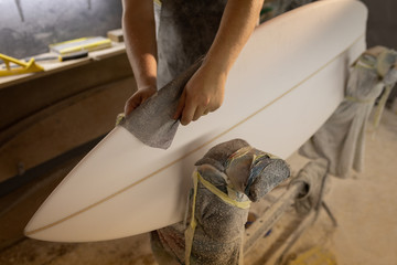 Man cleaning surfboard in a workshop
