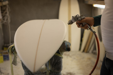 Man painting a surfboard in workshop