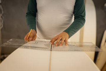 Man measuring a surfboard in workshop