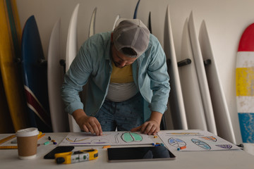 Man drawing surfboard sketch in a workshop