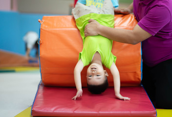 Little toddler boy working out at the indoor gym excercise - obrazy, fototapety, plakaty