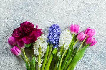 Beautiful bouquet of fresh tulips, peony and hyacinth on a light stone background. Top view, copy space