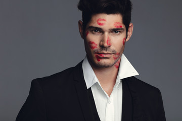 Attractive man with lipstick marks on face