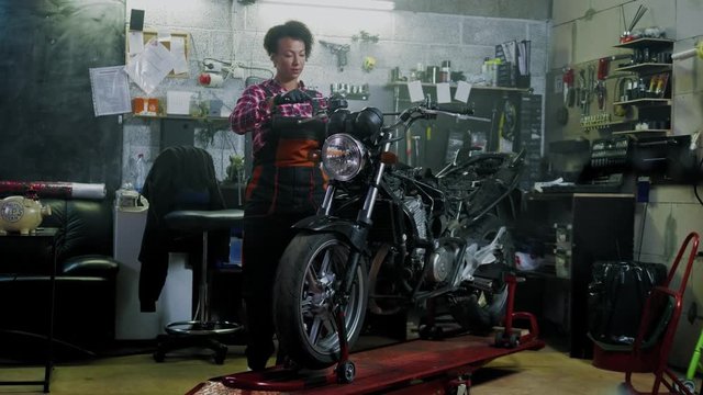 African american woman mechanic repairing a motorcycle in a workshop