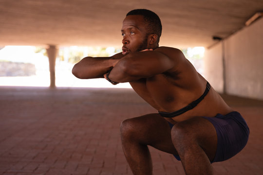 Man doing squat exercise under the bridge