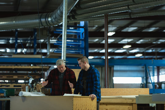 Caucasians male carpenters standing and discussing with each other at workshop