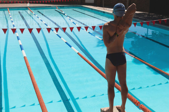Young male swimmer stretching at swimming pool