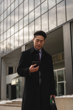 Asian businessman using mobile phone on street