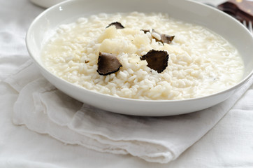 Risotto with black truffle and parmesan cheese  on white linen tablecloth, Copyspace.