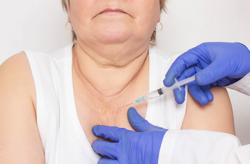 Doctor injects mesotherapy and biorevitalization of an elderly woman to the decollete area against...