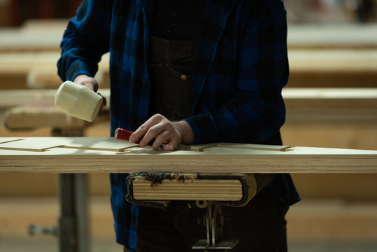 Carpenter using chisel with hammer in workshop 