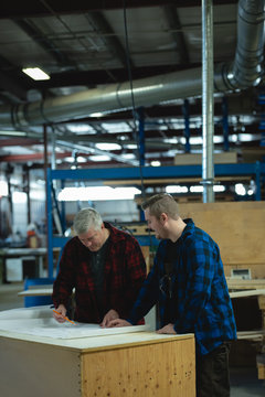 Caucasians male carpenters discussing and measuring at workshop
