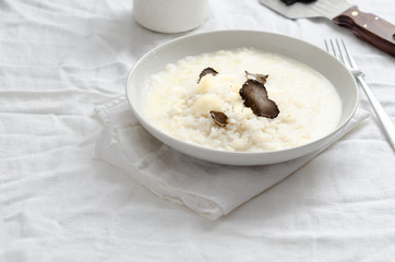 Risotto with black truffle and parmesan cheese  on white linen tablecloth, Copyspace.