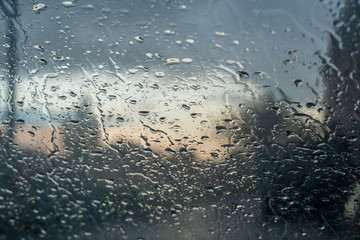 Background of water droplets on the windshield on a rainy evening with sun patterns