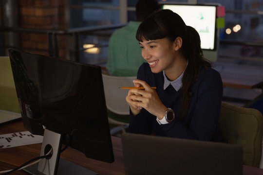 Businesswoman smiling while looking at computer in office 