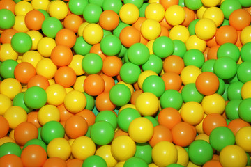 background of colored plastic balls (green, yellow, orange) for a child's game. Colorful background, texture.
