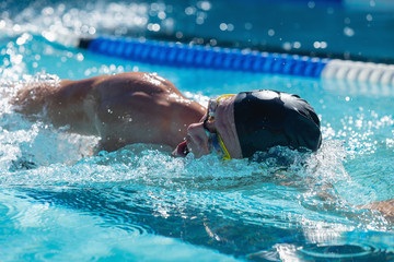 Male swimmer swimming freestyle in swimming pool