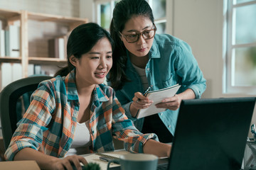 Startup team concept. two business woman people discussing together looking at laptop computer in bright cozy office. group of colleagues joyful talking listen working in modern studio workplace.