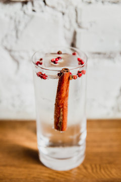 A vertical image of a refreshing gin and tonic with cinnamon and rose pepper in a highball glass. Selective focus.