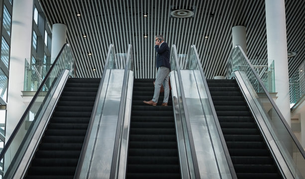 Businessman talking on the mobile phone on escalator