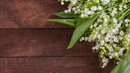 bouquet of white lilies of the valley on a brown wooden background with a copy of space