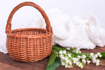 Fototapeta na wymiar bouquet of white lilies of the valley with a basket on a brown wooden background with a copy of space